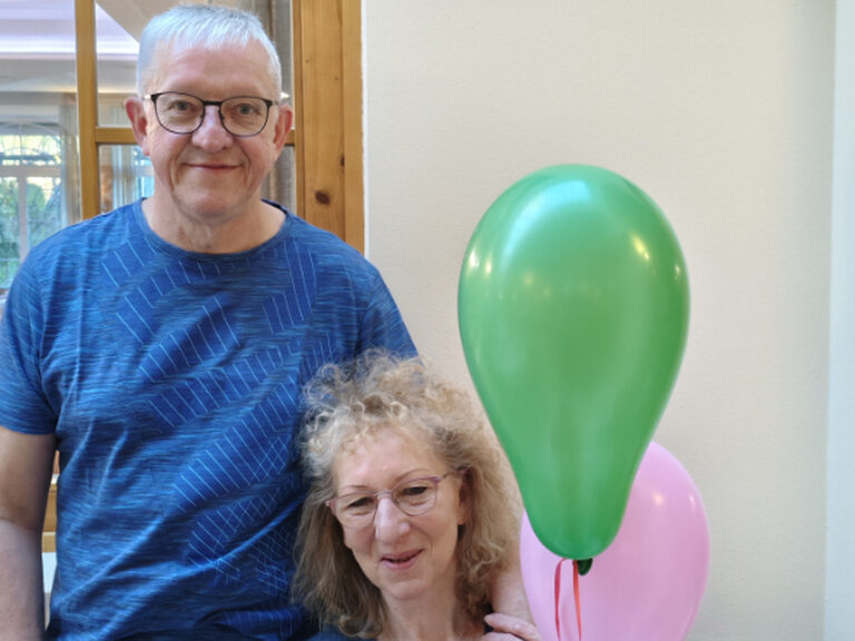 Paar posiert anlässlich Geburtstag mit bunten Luftballonen