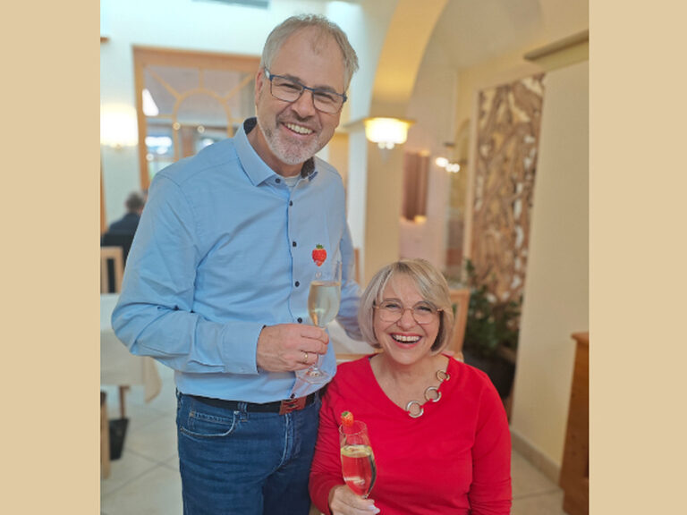 Paar posiert mit einem Glas Sekt anlässlich des Geburstags des Mannes