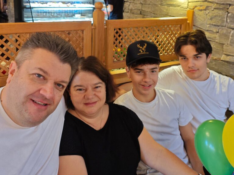 Familie sitzt und lächelt in die Kamera anlässlich eines Geburtstags