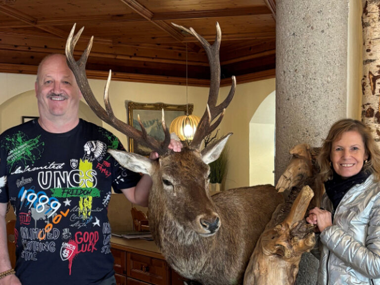 Paar posiert neben einem ausgstopften Hirsch anlässlich eines Geburtstags