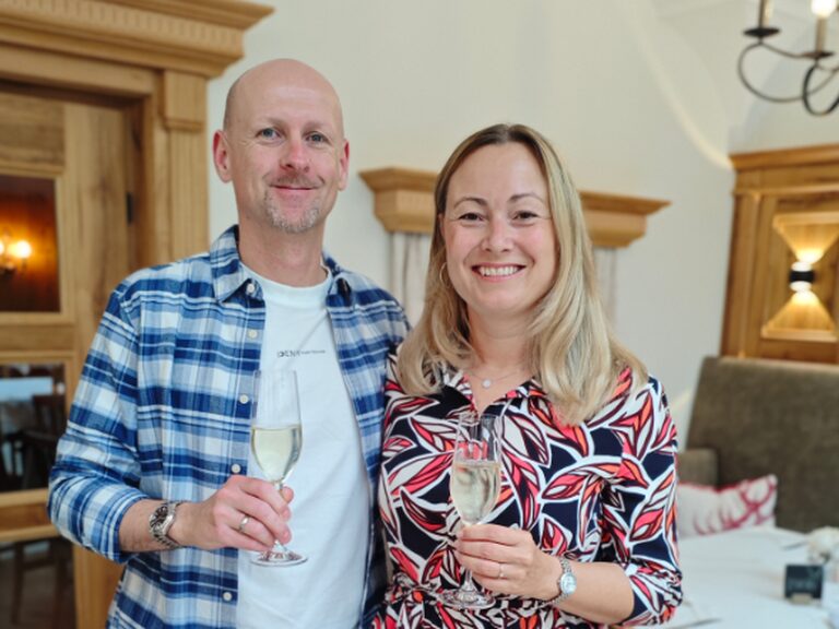 Paar strahlt und posiert mit einem Glas Sekt anlässlich eines Geburtstags