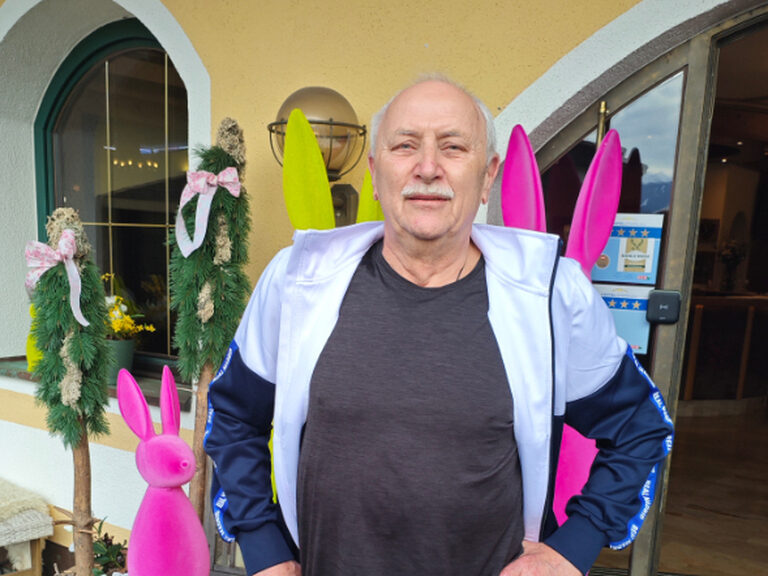 Ein Mann steht vor dem Kohlerhof und posiert anlässlich seines Geburtstags; im Hintergrund ist Osterdeko zu sehen