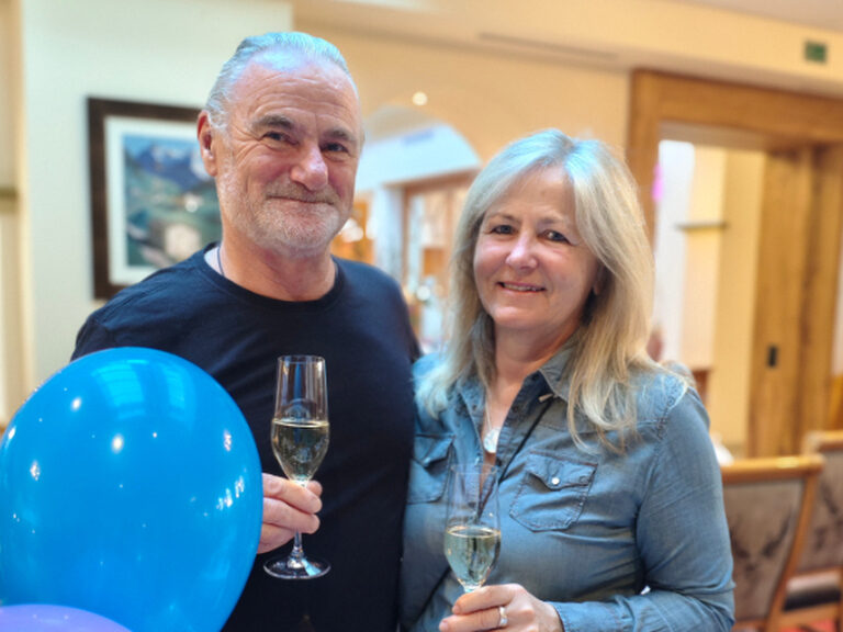 Paar posiert anlässlich eines Geburtstags mit einem Glas Sekt