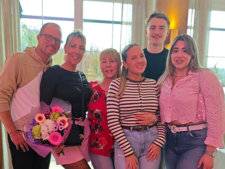 Familie posiert fröhlich mit einem bunten Blumenstrauß anlässlich eines Geburtstags