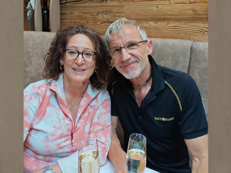 Paar sitzt mit je einem Glas Sekt am Tisch