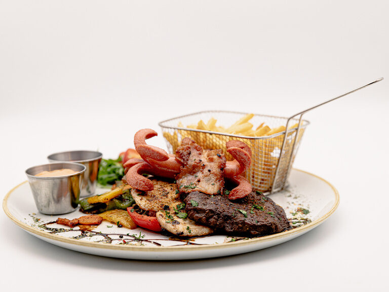 Grillteller mit mehreren Fleischsorten, Gemüse und Dips