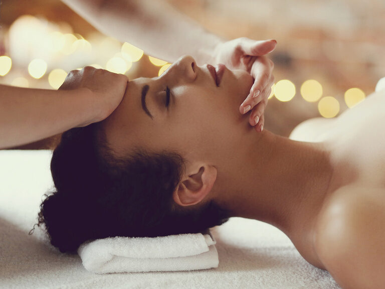 Frau auf einer Liege, deren Gesicht massiert wird