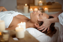 Frau liegt auf einer Massageliege und wird am Kopf massiert