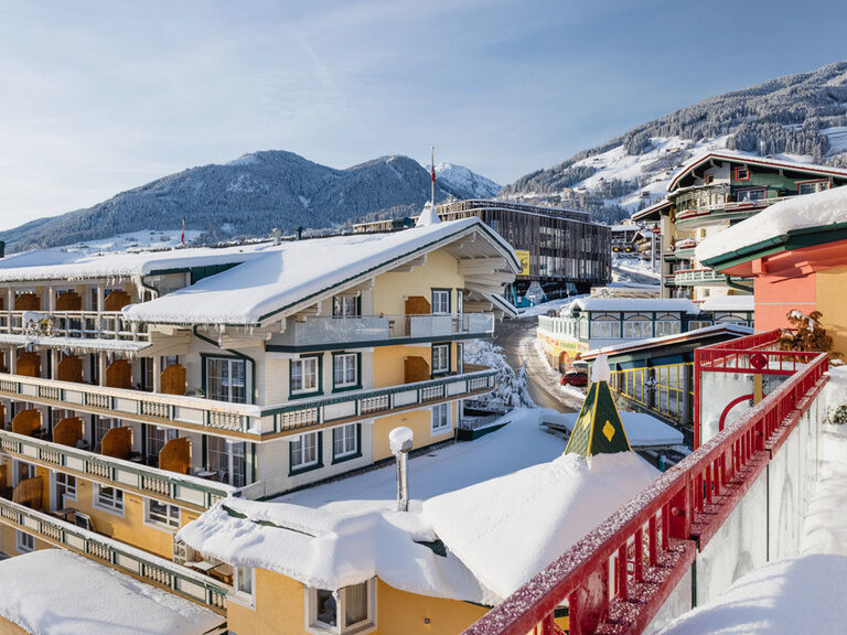 Blick auf den verschneiten Kohlerhof im Winter, mit Zillertaler Bergen die mit Schnee bedeckt sind im Hintergrund.
