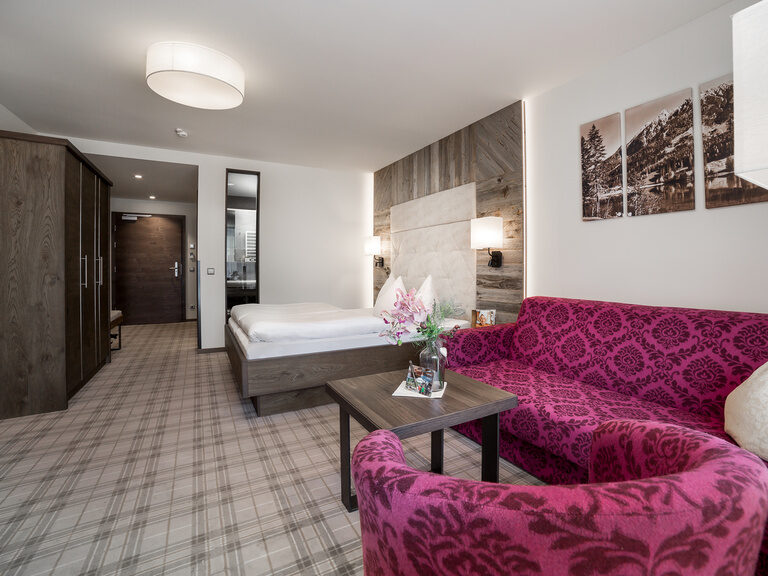 Kuschelsuite mit Doppelbett, Teppichboden und pinker Sitzecke