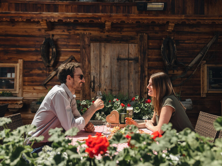 Paar sitzt an einem Tisch auf der Terrasse und trinkt Bier sowie Schnaps