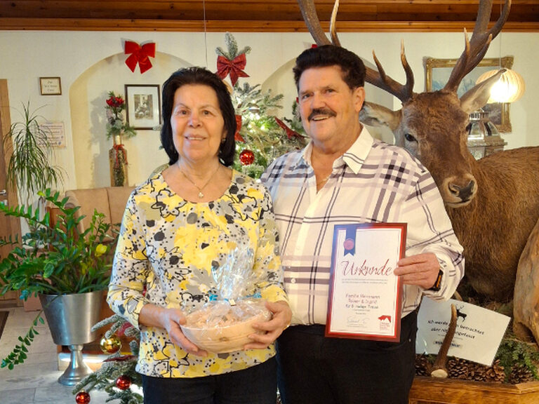 Paar posiert mit Gästeehrungsurkunde