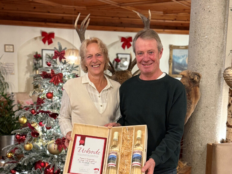 Paar lächelt fröhlich mit der Stammgäste-Urkunde in die Kamera