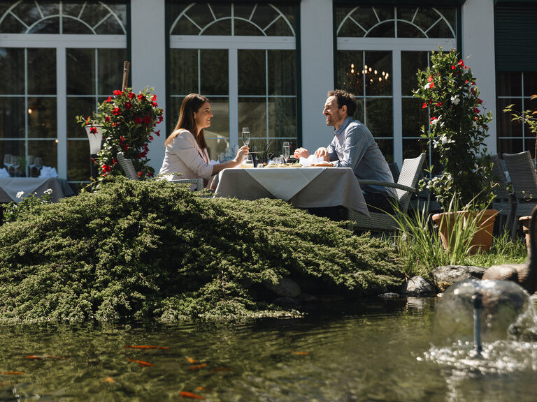 Paar sitzt beim romantischen Dinner mit Sekt auf der Gastterrasse