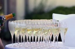 Champagnergläser stehen auf einem Stehtisch und werden mit Champagner befüllt