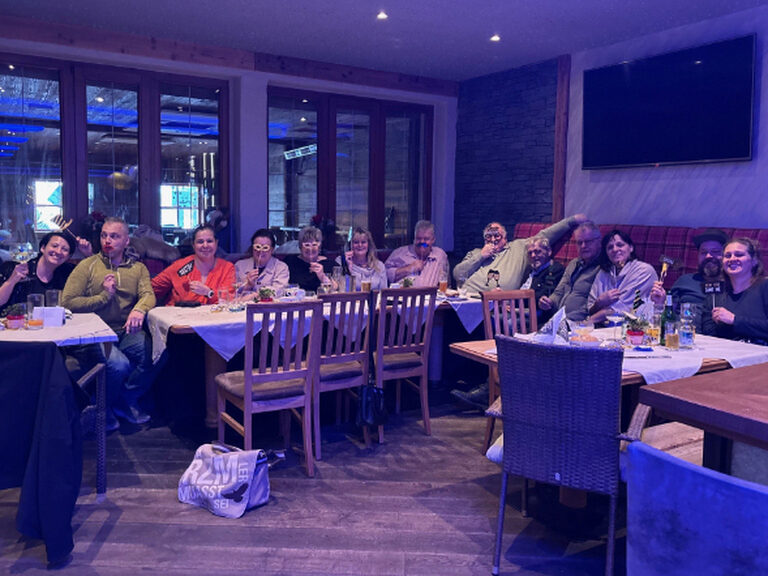 Mehrere Personen sitzen am Frühstückstisch und posieren mit lustigen Pappmasken