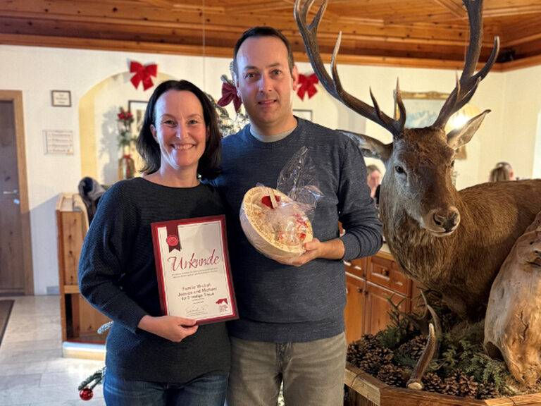 Paar posiert mit Urkunde und Geschenk vom Hotel anlässlich Stammgästeehrung