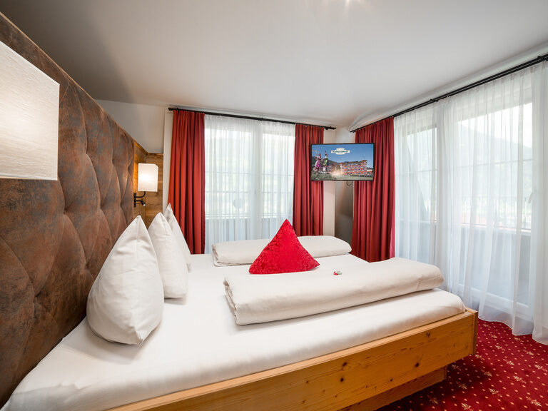 Superior Kaisersuite Das Zillertal mit Doppelbett, rotem Teppich und Holzvertäfelung