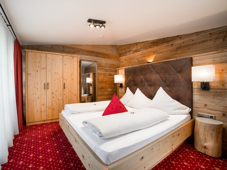 Superior Kaisersuite Das Zillertal mit Doppelbett, rotem Teppich und Holzvertäfelung